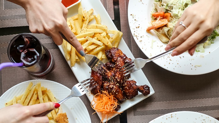 Top View Women Eating Barbecue Chicken Wings With Fries Salad With Juice Table